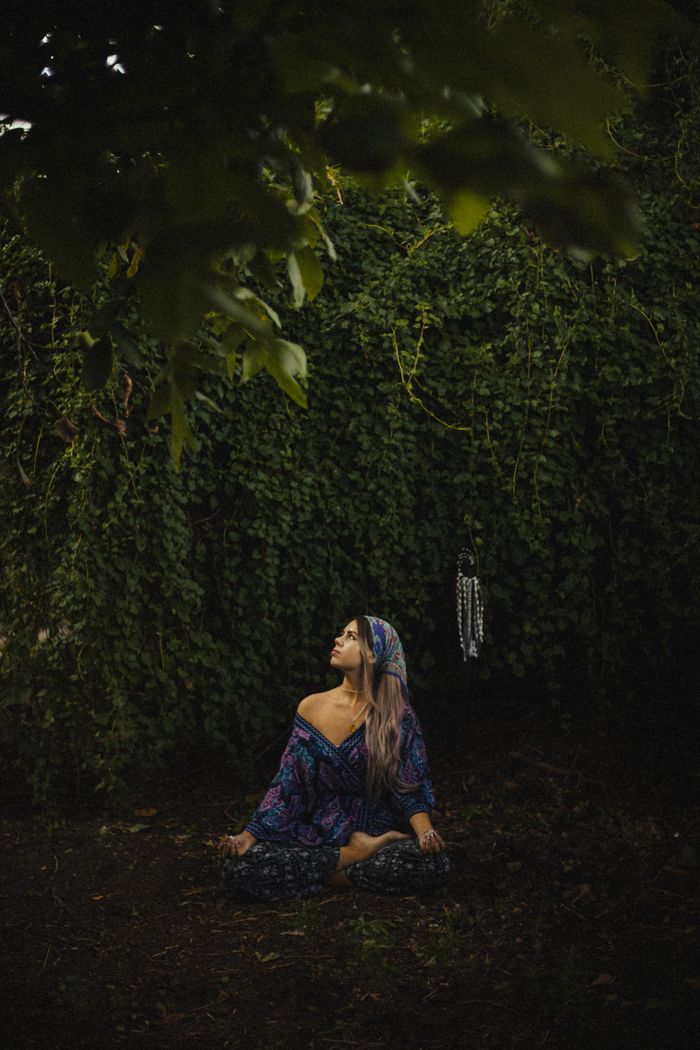 A woman sits in meditation amidst lush greenery, embodying peace and mindfulness in nature.